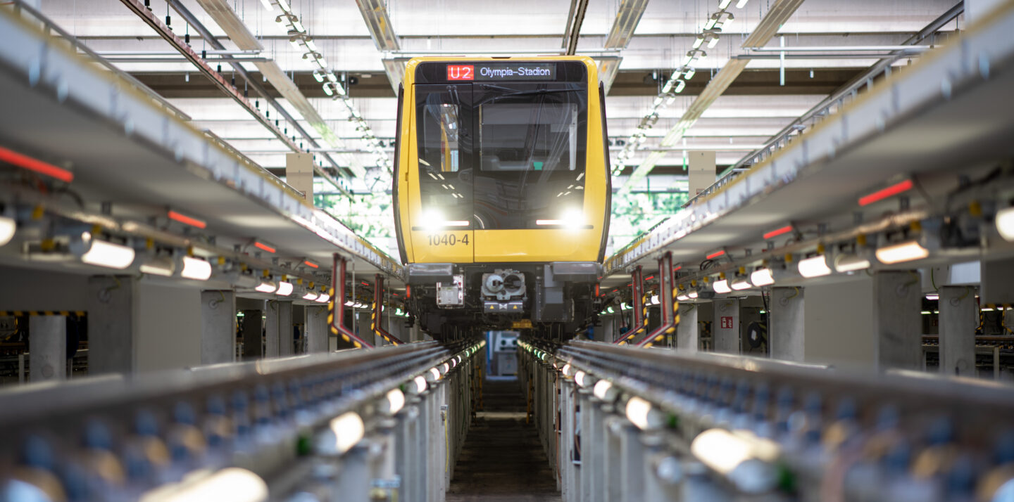 Bild aus einer BVG-Werkstatt: Eine U-Bahn ist zur Wartung aufgebockt. Ihre Scheinwerfer strahlen durch die Werkstatt.