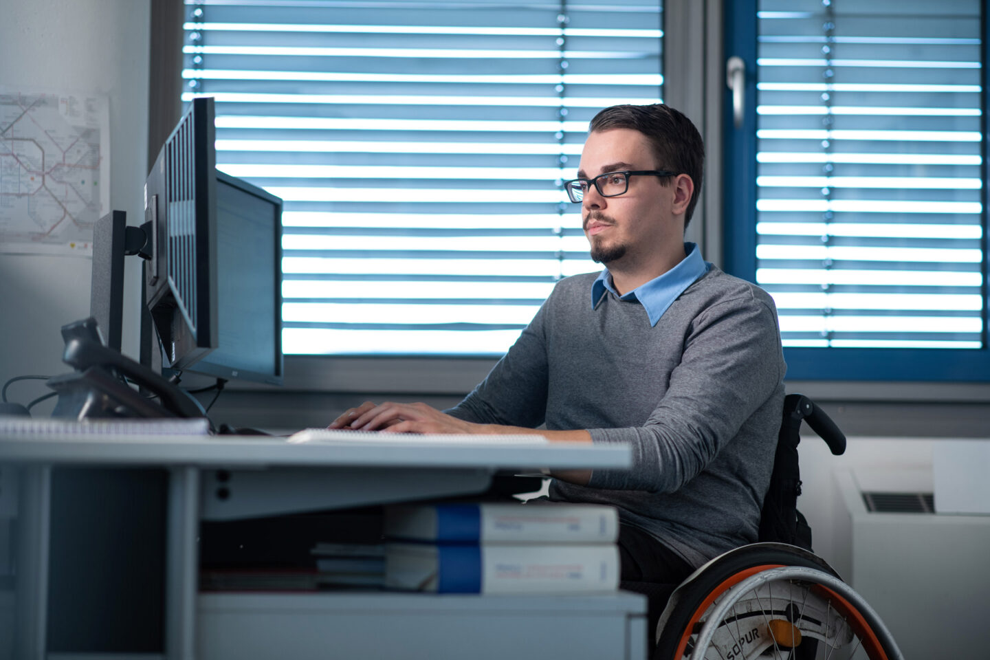 Marcel arbeitet als Kaufmann bei der BVG und sitzt in seinem Rollstuhl am Arbeitsplatz.