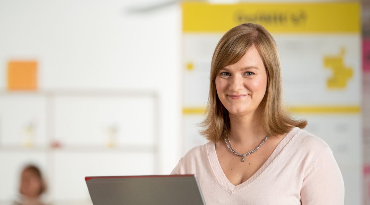 IT-Mitarbeiterin Antje steht in ihrem BVG-Büro am Laptop und arbeitet.