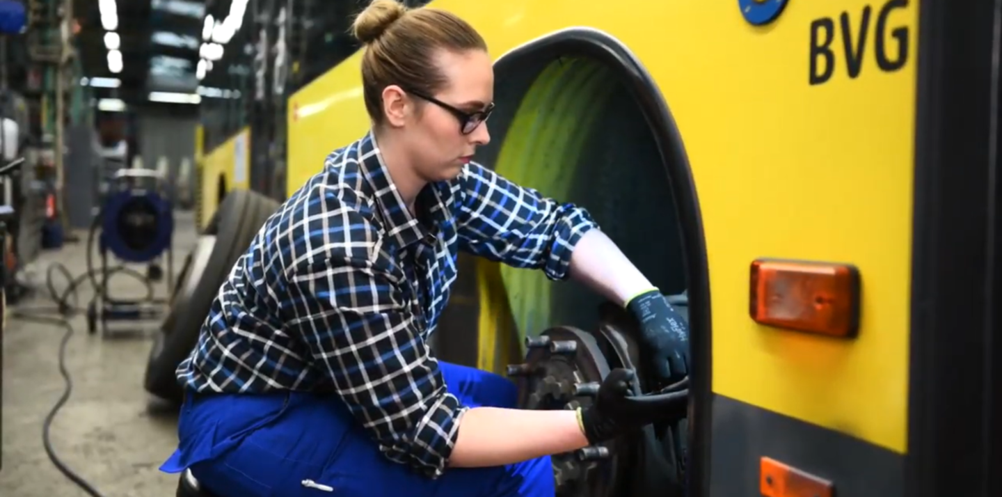 Auszubildende als Kfz-Mechatronikerin repariert einen Bus