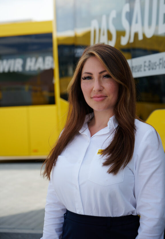 Fatima steht vor einem gelben BVG-Bus