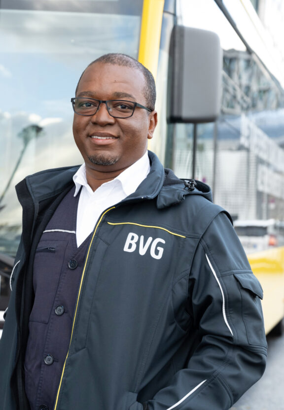Busfahrer Salem steht in BVG-FAhrdienstkleidung vor einem Bus