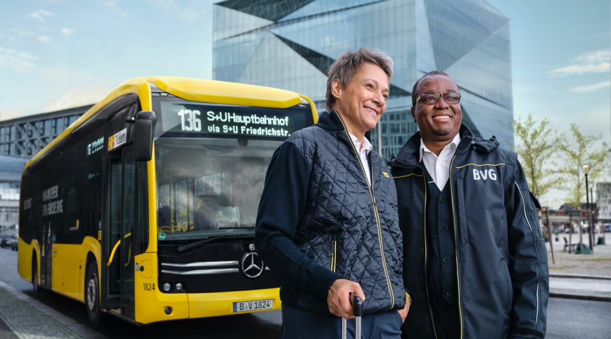 Eine Frau und ein Mann stehen in Fahrdienstkleidung der BVG vor einem Bus in Berlin Mitte vor dem Cube-Gebäude