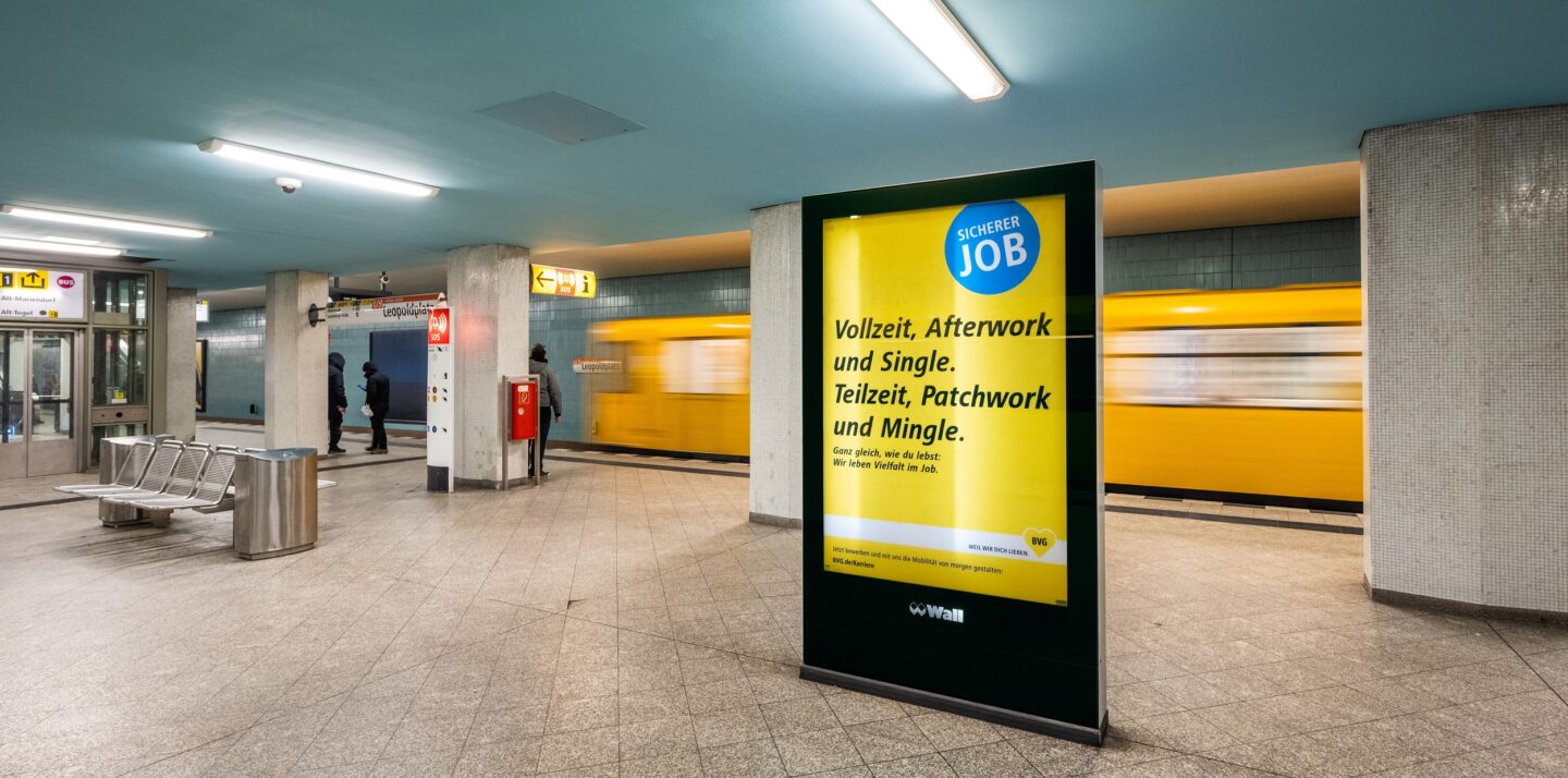 Ein beleuchtetes Werbeplakat steht an der U-Bahnstation. Die Aufschrift: 