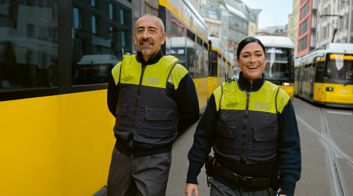 Mann und Frau vom Sicherheitsdienst, vor Straßenbahn