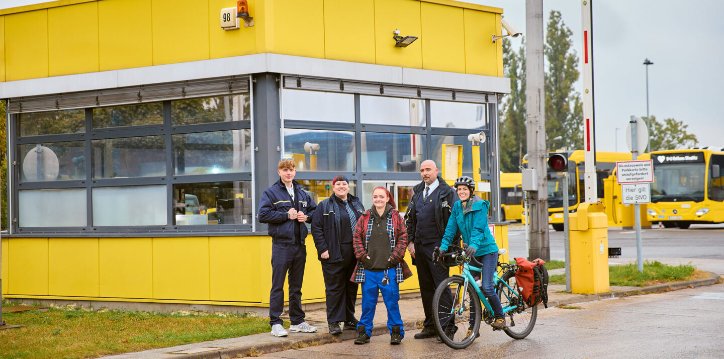 Fünf Mitarbeitende stehen vor einem gelben Pförtnerhäuschen auf dem Betriebshof