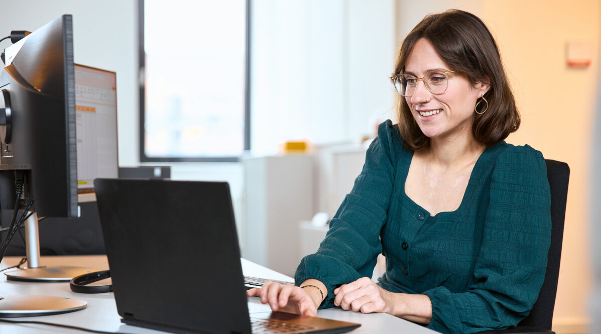 Mitarbeiterin sitzt am Schreibtisch und arbeitet am Laptop.