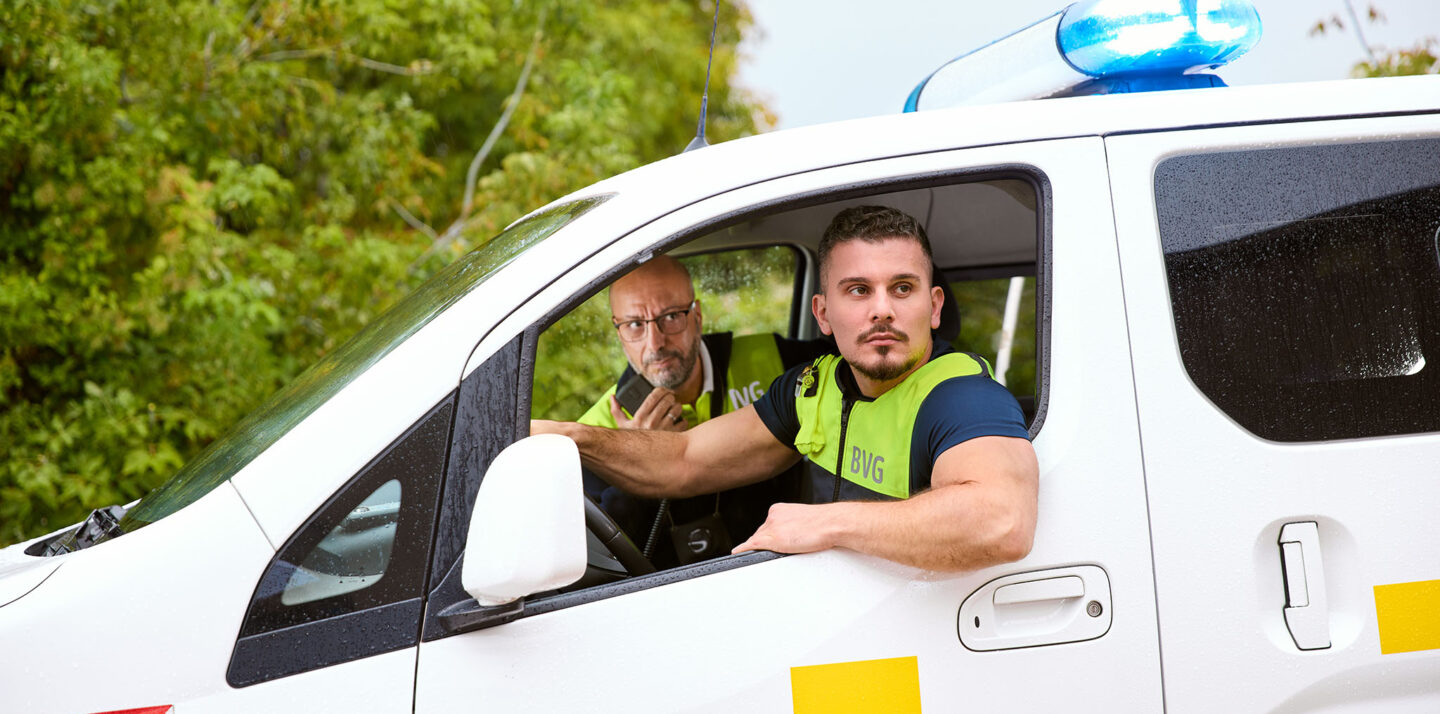 Zwei Männer vom BVG-Objektschutz sitzen im Auto und schauen aus dem offenen Fenster