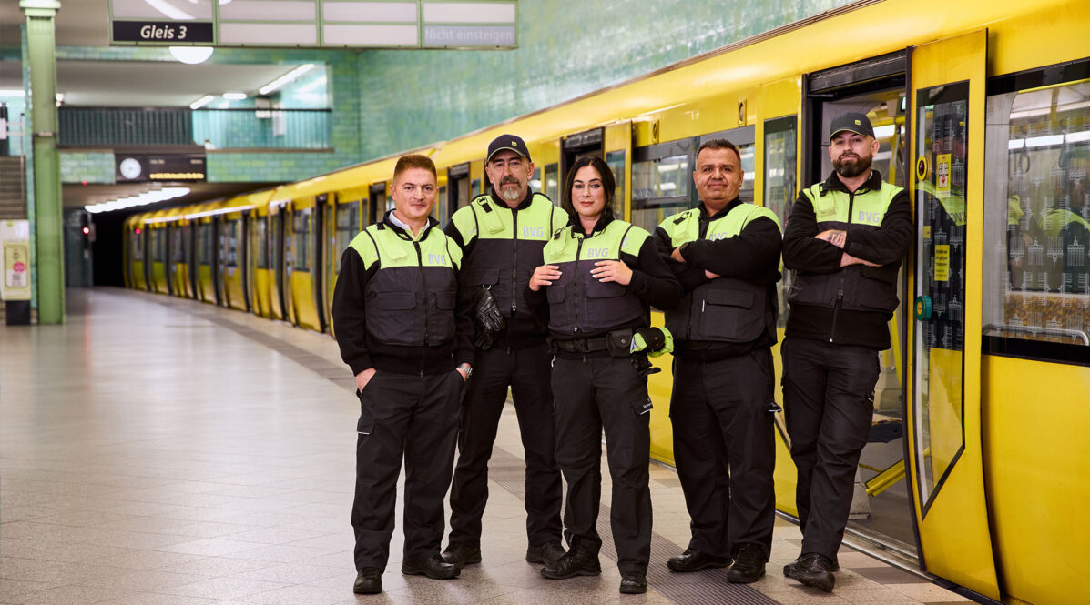 Fünf Mitarbeitende aus dem Sicherheitsdienst stehen vor einer U-Bahn.